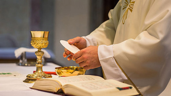Un prêtre préparant la communion durant une messe eucharistique