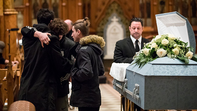 Des jeunes se reccueillent devant le cercueil de "Pops", une figure marquante pour plusieurs.