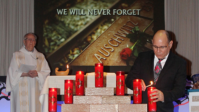 Fr. John Baxter looks on as Jorge Falla Luque, an ecumenical animator with the Université de Québec à Montréal, lights the seventh memorial candle.