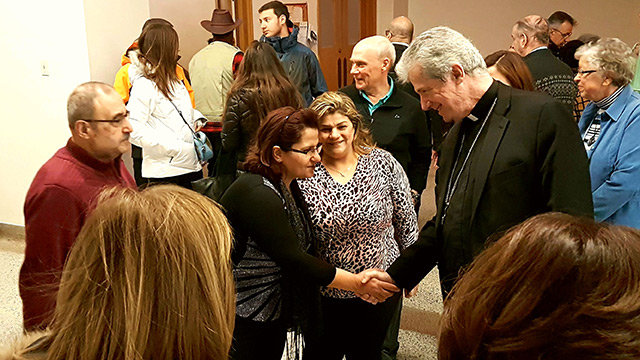 Mgr Lépine qui accueille des familles de réfugiés